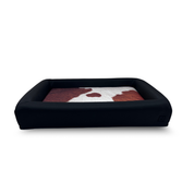 Cowhide waterproof dog bed with black bolster and removable washable covers.