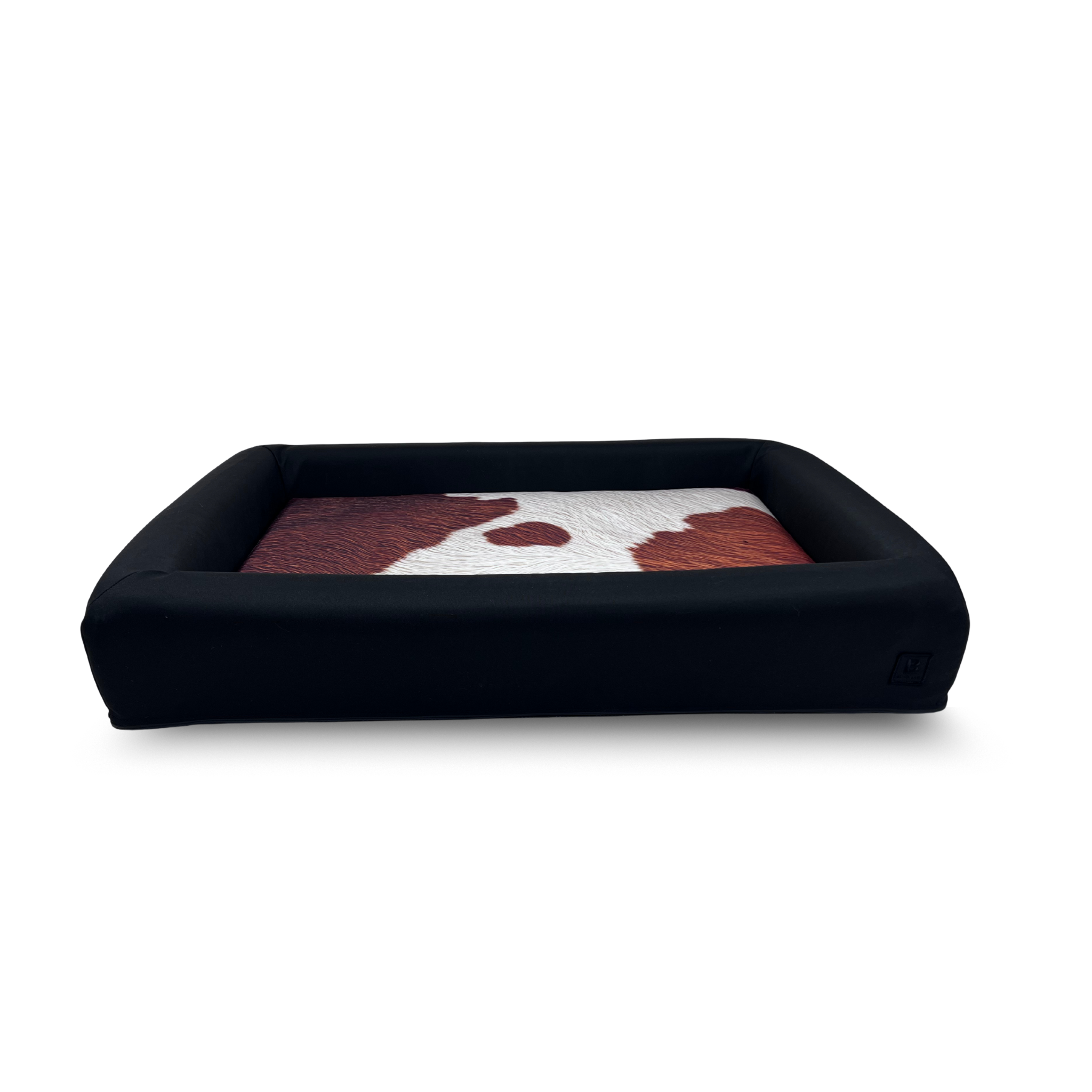 Cowhide waterproof dog bed with black bolster and removable washable covers.