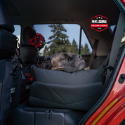 Dog resting on a pet seat cover in the back of a vehicle with 'Men's Journal Editor's Choice' badge.