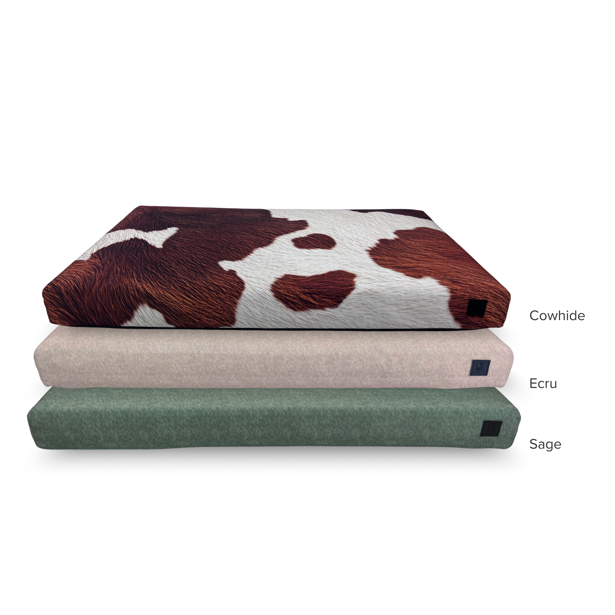 Stack of three dog beds displaying cowhide, sage, and ecru color bed covers.